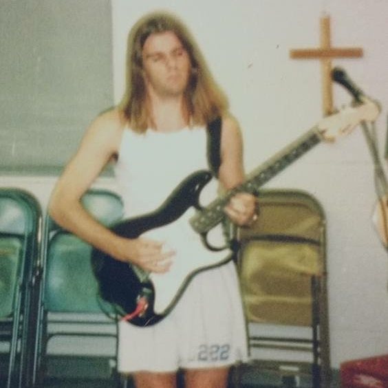 A teenage Nathan Adam playing electric guitar in a church hall