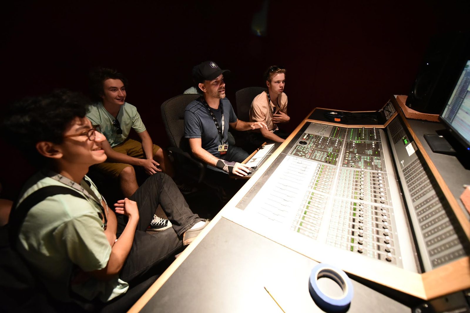 Nathan Adam and GRAMMY Camp students gathered around a large recording console