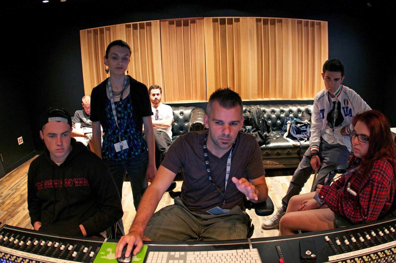 Nathan Adam sitting at a console with a group of students in a recording studio