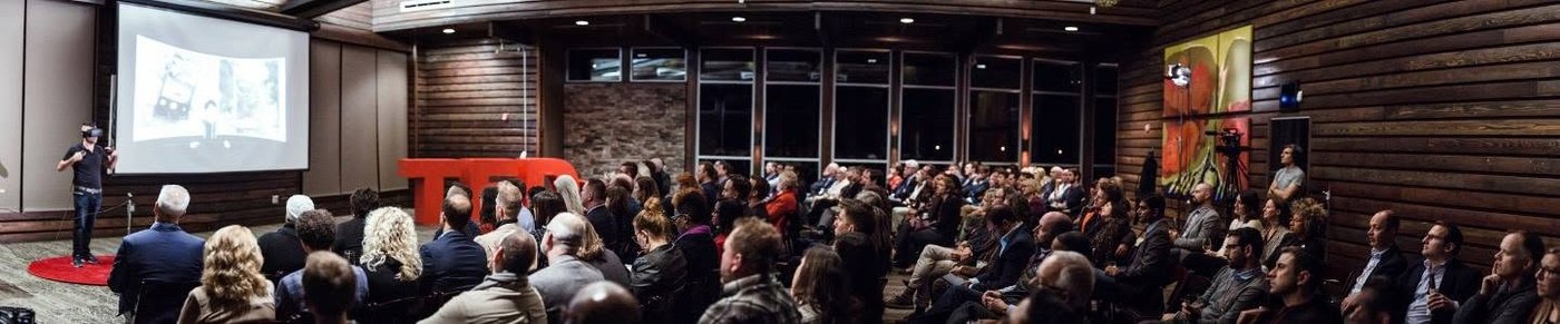 Panorama of a full TEDxNashville audience facing the stage, with a camera operator at the back of the room